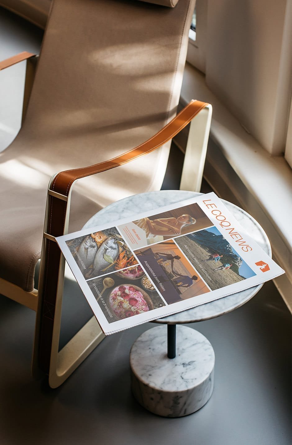 Lifestyle newspaper on a round marble table beside a designer chair